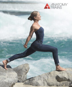 woman stretches across rocks on the beach